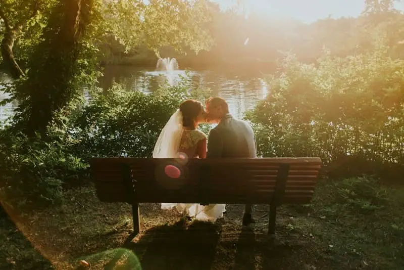 couple de mariés sur un banc dans le parc du Château de la Pervenchère